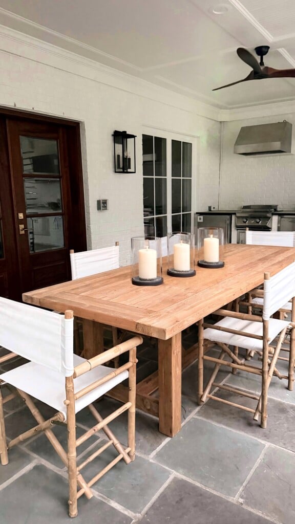 Bamboo folding director chairs and teak dining table on covered patio with outdoor kitchen