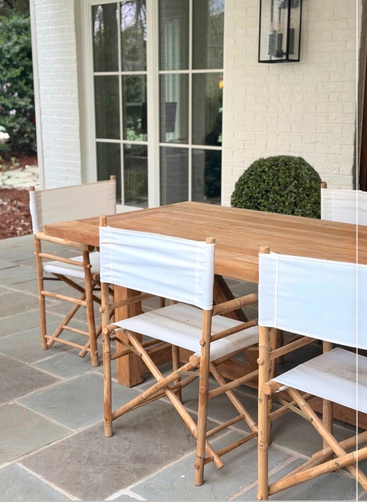 White canvas director chairs around teak table on bluestone patio
