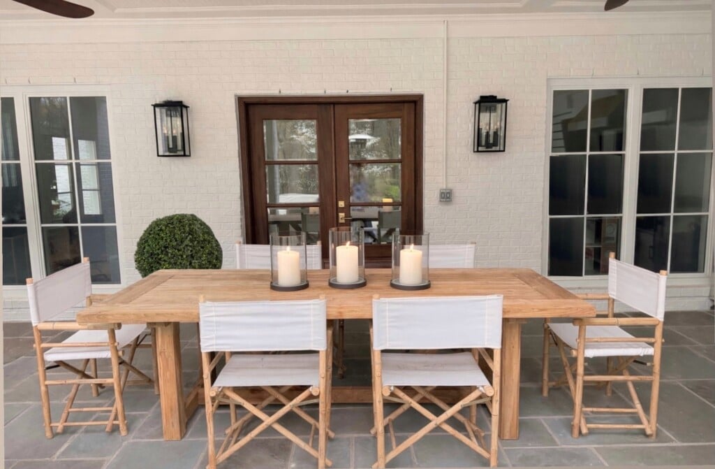 Six Yohana folding director chairs around a teak dining table on a covered patio